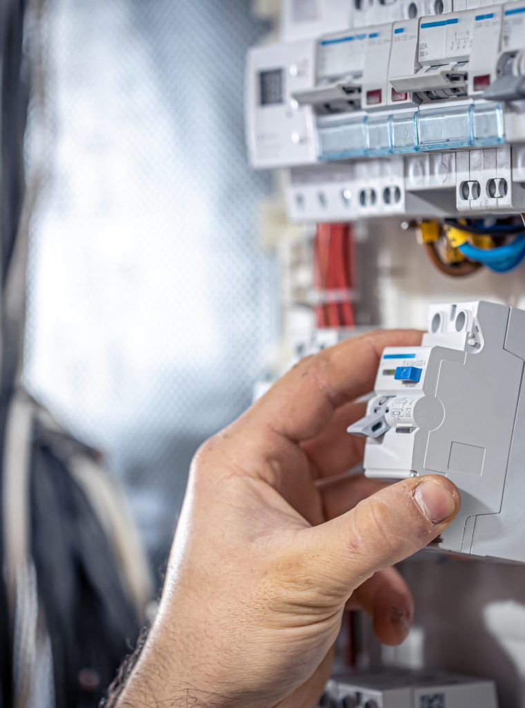 Male electrician at the checkout counter on a blurred background of a switchboard.